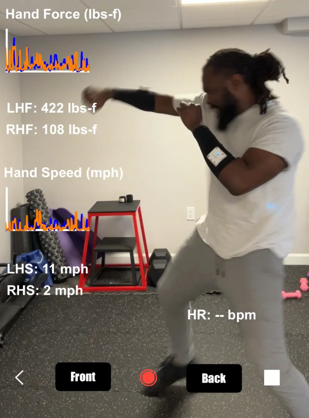 Man boxing indoors with hand force and speed data displayed on screen, highlighting real-time athletic performance tracking.